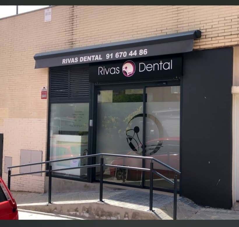 Fachada de la clínica Rivas Dental con toldo negro, letrero y rampa de acceso metálica.